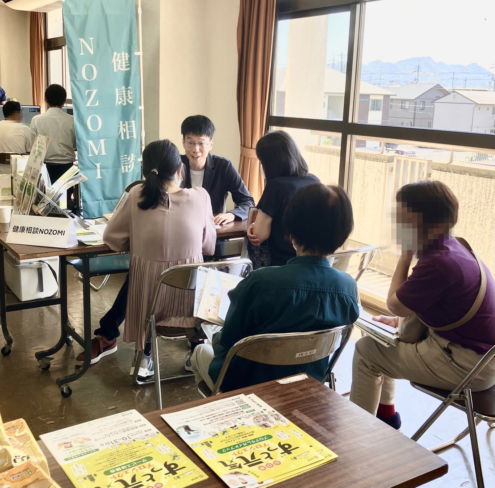9月30日サービス体験会 健康相談NOZOMIブースでお話をうかがう山本と、順番をお待ちいただく来場者の方々